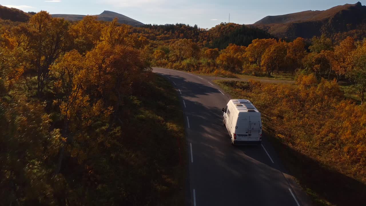 Winding road through colorful autumn forest in Vestarelen, Norway with clear skies