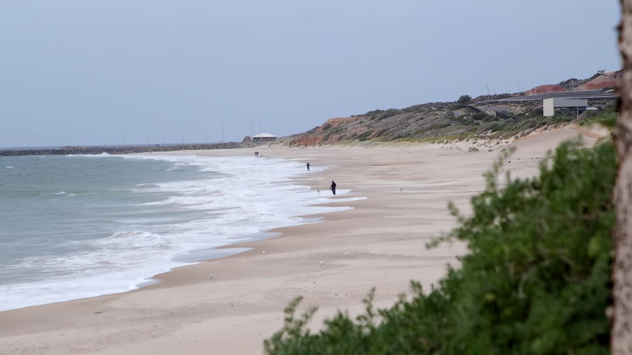 pescando en la playa en un día frío y nublado