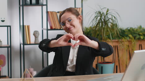 caucasian business woman makes symbol of love showing heart sign to camera express romantic feelings