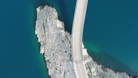 an aerial over road curve entering bridge and stoney rugged coast