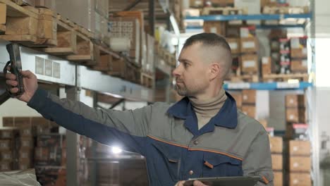 el gerente utiliza el escáner para comprobar las mercancías en los estantes del centro de distribución