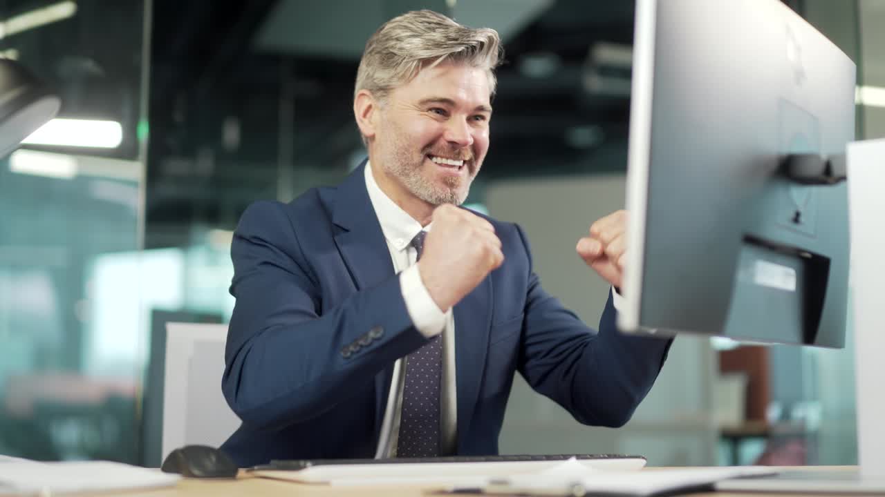 Successful Mature Businessman Wearing Suit Sitting At Desk With Laptop In Office. Portrait of a confident mid age gray hair male in the workplace working at a computer