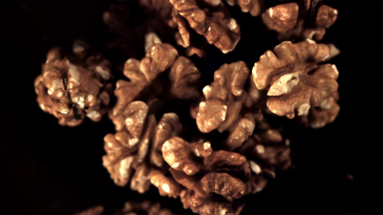 Shelled Walnuts Sharpening into Focus Against a Dark Background