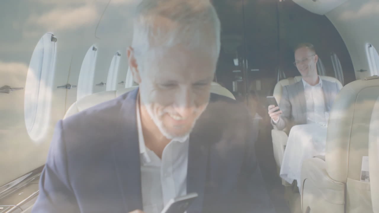 Businessmen using smartphones on private jet with cloud animation overlay