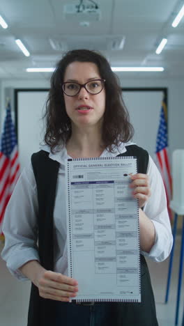 american female voter speaks on camera shows paper ballot american female voter or polling officer speaks on camera shows paper ballot calls for voting national election day in the united states voting booths at polling station civic duty and patriotism