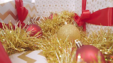 Golden-Christmas-tinsel,-presents-and-sparkly-baubles-with-camera-pulling-away