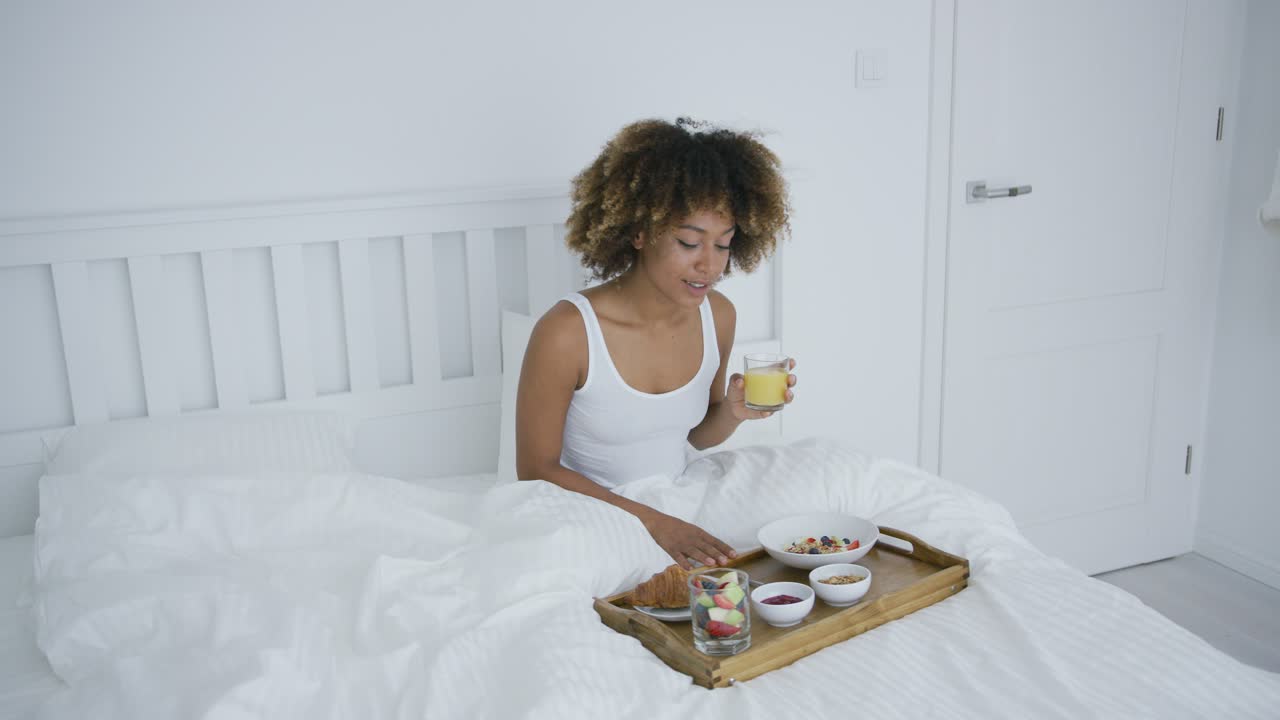 Donna con smartphone a letto che consuma un pasto