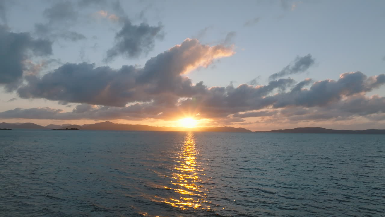 Drone flying over the ocean as the sunrise bursts through the horizon in the Whitsunday islands, QLD, Australia