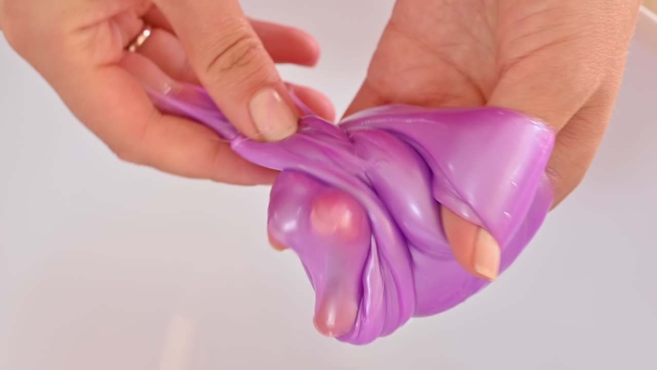 Punaisessa mekossa oleva nainen leikkii violetilla limalla valkoisella lautasella