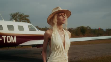 woman in a straw hat by a private jet