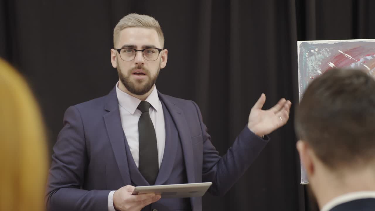 Male Auctioneer Giving Presentation about Painting to Audience