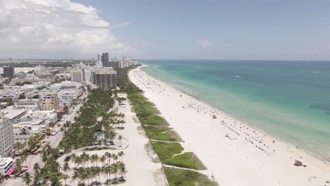 low aerial flight over tropical urban sand beach and turquoise ocean