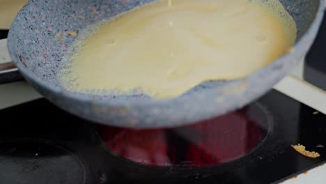 Batter slowly poured into pan as homemade crepes begin to sizzle and take shape
