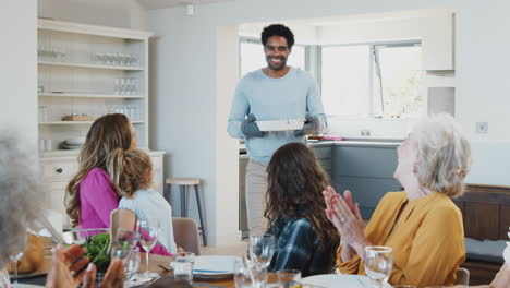 Vater-Serviert-Essen,-Während-Sich-Eine-Familie-Mit-Mehreren-Generationen-Zu-Hause-Zum-Essen-Trifft