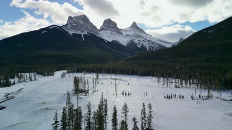 Antena-De-Tres-Hermanas-Cumbres-Nevadas-Con-área-Boscosa-En-El-Valle,-Canmore,-Alberta,-Canadá