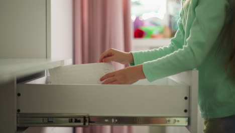 Little-girl-takes-out-files-and-papers-of-drawer-in-room