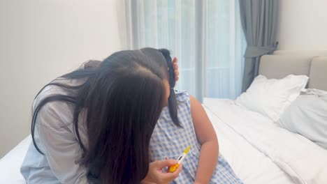 a mother cares for her unwell daughter in a softly lit bedroom, offering comfort and checking her temperature