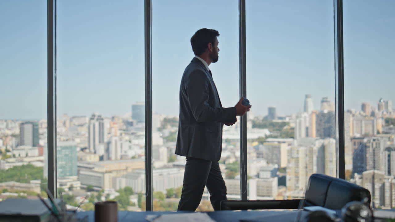 hombre de negocios preocupado caminando en la oficina de la viuda panorámica. hombre lanzando la pelota