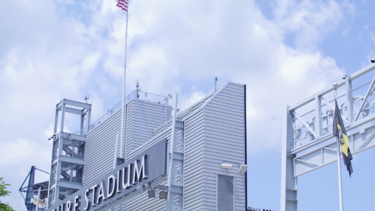 Exterior views of Acrisure Stadium, featuring trees and the American flag
