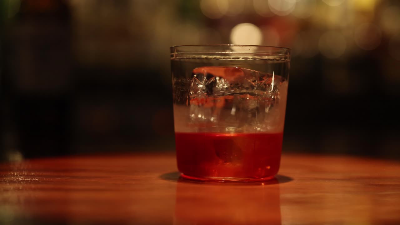 mano agitando una bebida con hielo en un bar