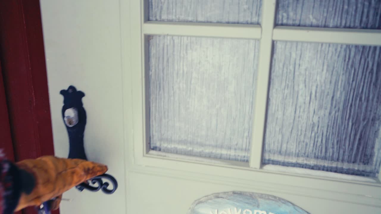 겨울 옷을 입은 사람의 손이 잠금 해제되고 집에 들어가기 위해 문을 여는 것