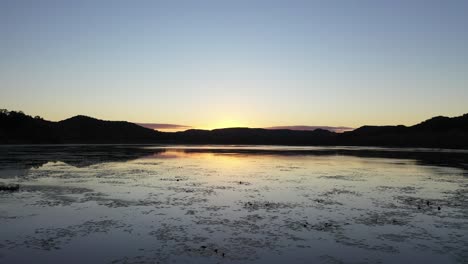 sunrise over a tranquil lake with reflections and mountains