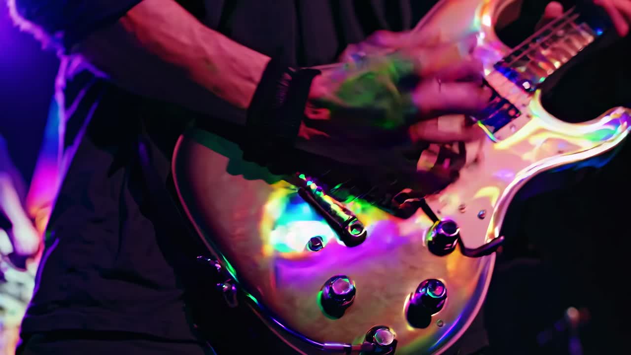Close-up video of a guitarist's hands playing an electric guitar, showcasing vibrant stage lighting