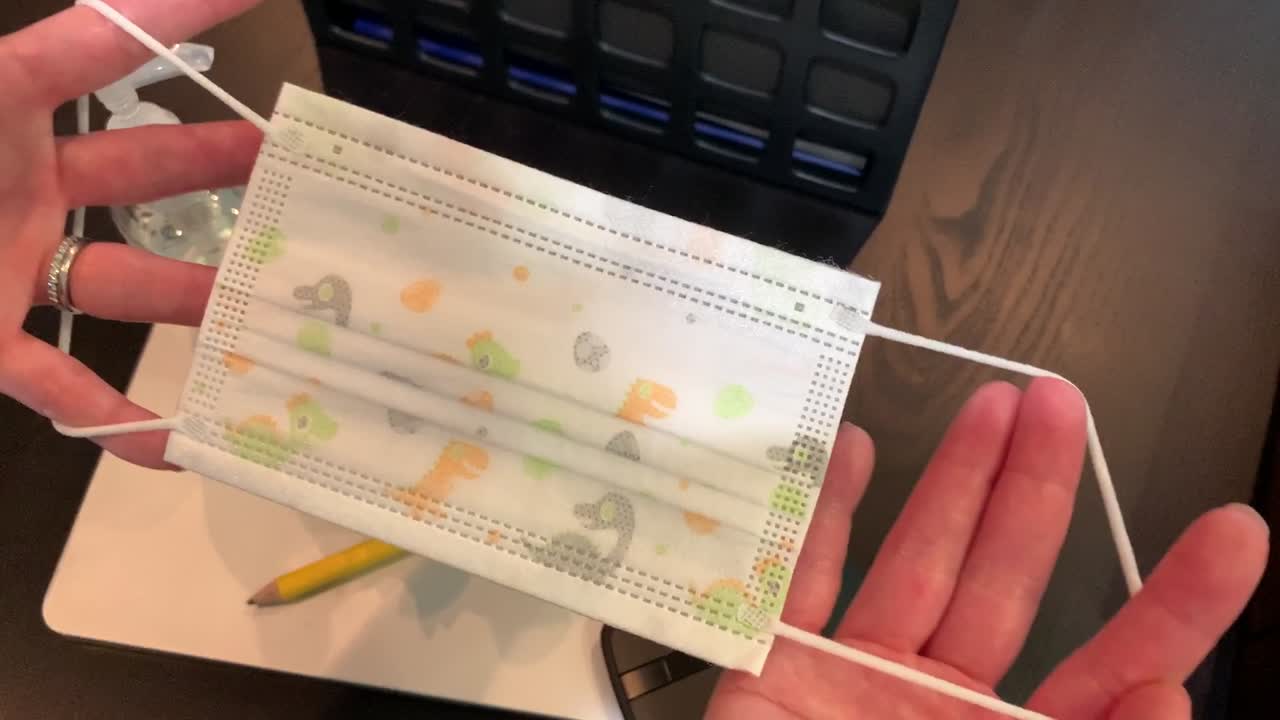 외부에 공룡 프린트가 있고 내부에 흰색이 있는 아이들을 위한 귀여운 일회용 얼굴 마스크