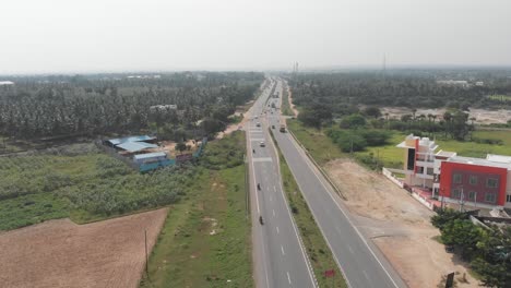 Beautiful-shot-of-cars-and-trucks-driving-down-a-highway-in-a-rural-area-of-India-during-a-sunny-day