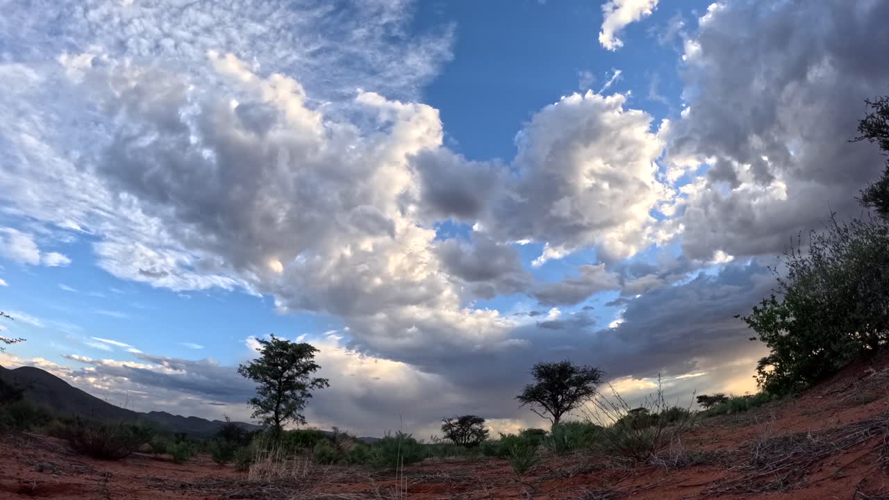 este breve lapso de tiempo captura la evolución dinámica y la graciosa danza de las nubes a través del impresionante paisaje africano del sur de kalahari.