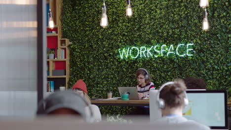 young business woman student using laptop computer in modern office working on project listening to music wearing headphones