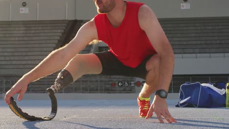 sección baja de un atleta masculino caucásico discapacitado con el estiramiento de la cuchilla de correr