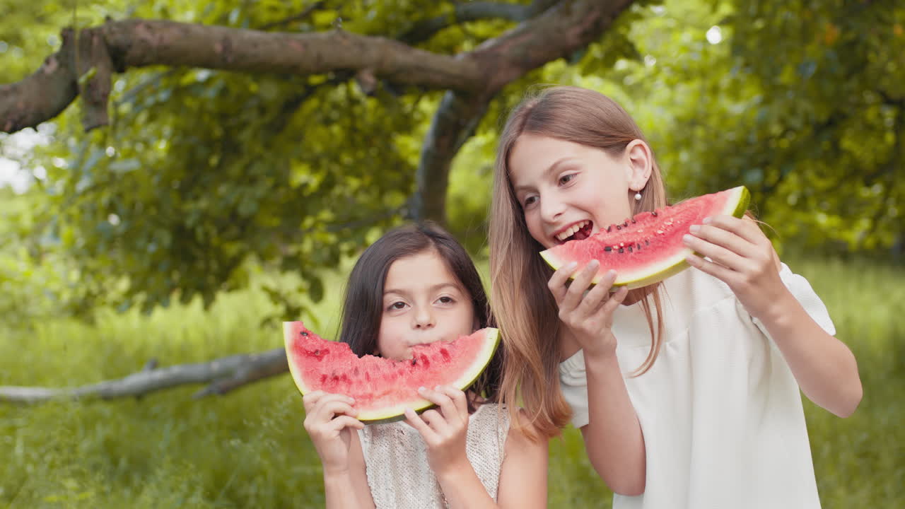 dos hermanas disfrutando de una sandía