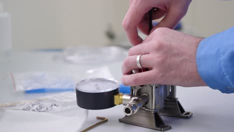 técnico que trabaja en el ensamblaje de medidores de presión y válvulas en un entorno de laboratorio