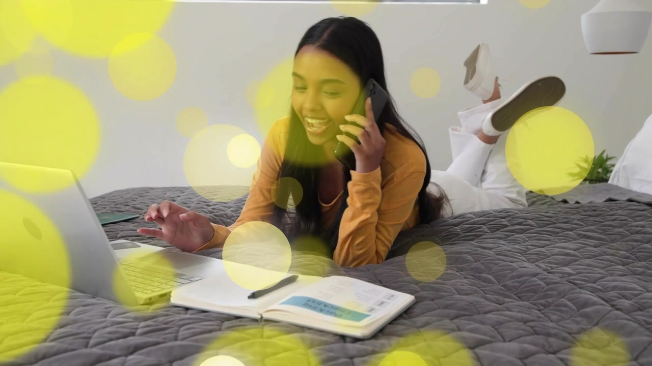 Woman on bed answering phone after ping, typing and noting for remote work, yellow bokeh overlay