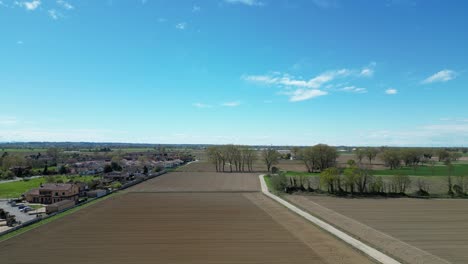 Drone-flies-over-houses-alongside-an-expanse-of-freshly-cultivated-corn-fields-in-the-Po-Valley-in-Italy