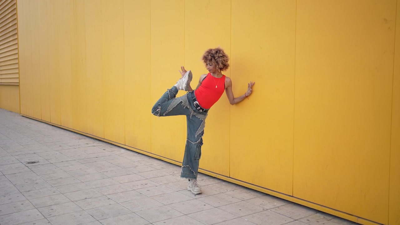 A young person walking confidently against a vibrant yellow wall showcasing energy and style