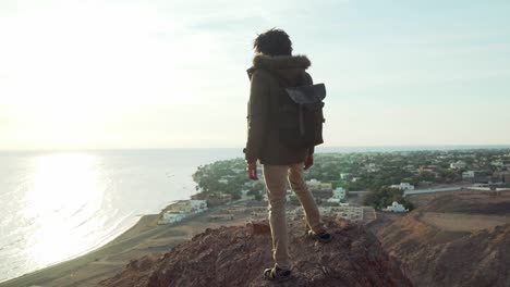 hombre adulto de oriente medio mirando el horizonte de pie en un acantilado al amanecer