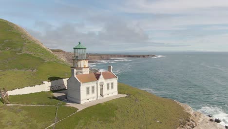 historic lighthouse on coastal cliff side, push in drone shot