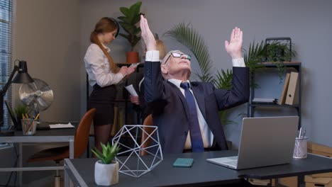 mature elderly freelancer man praying to god, looking upward and making wish good luck in office