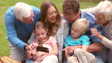 happy family smiling using smartphone in a park