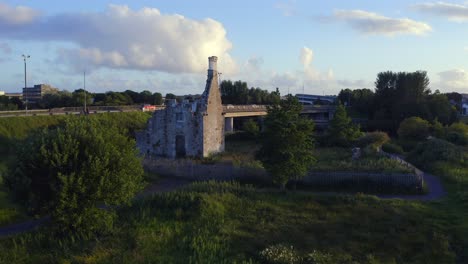 Angled-dolly-to-Terryland-Castle-on-River-Corrib,-Galway-Ireland,-with-highway-road-behind