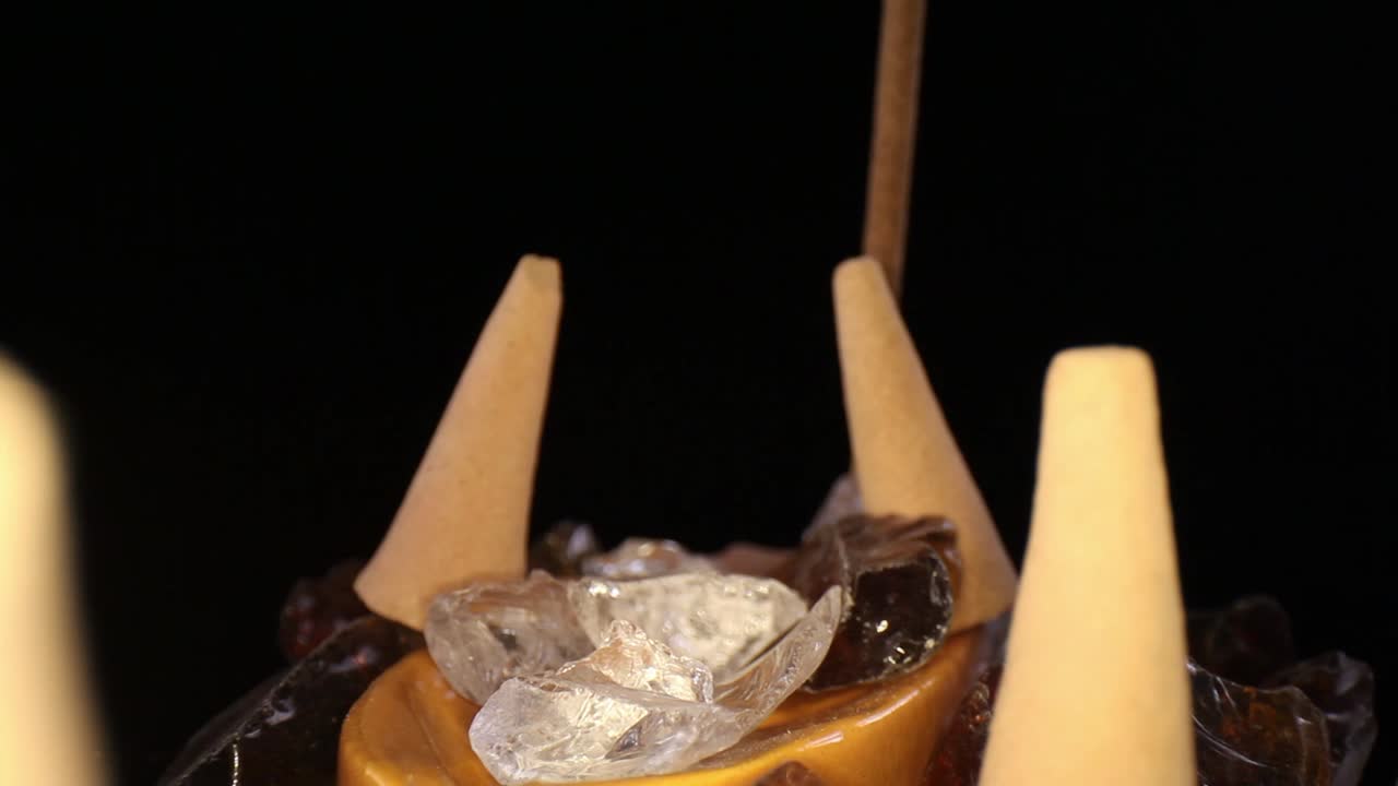 pasando rápidamente varios conos de incienso apagados en un jardín de rocas decorativo, alejándose de un palo que no está fumando