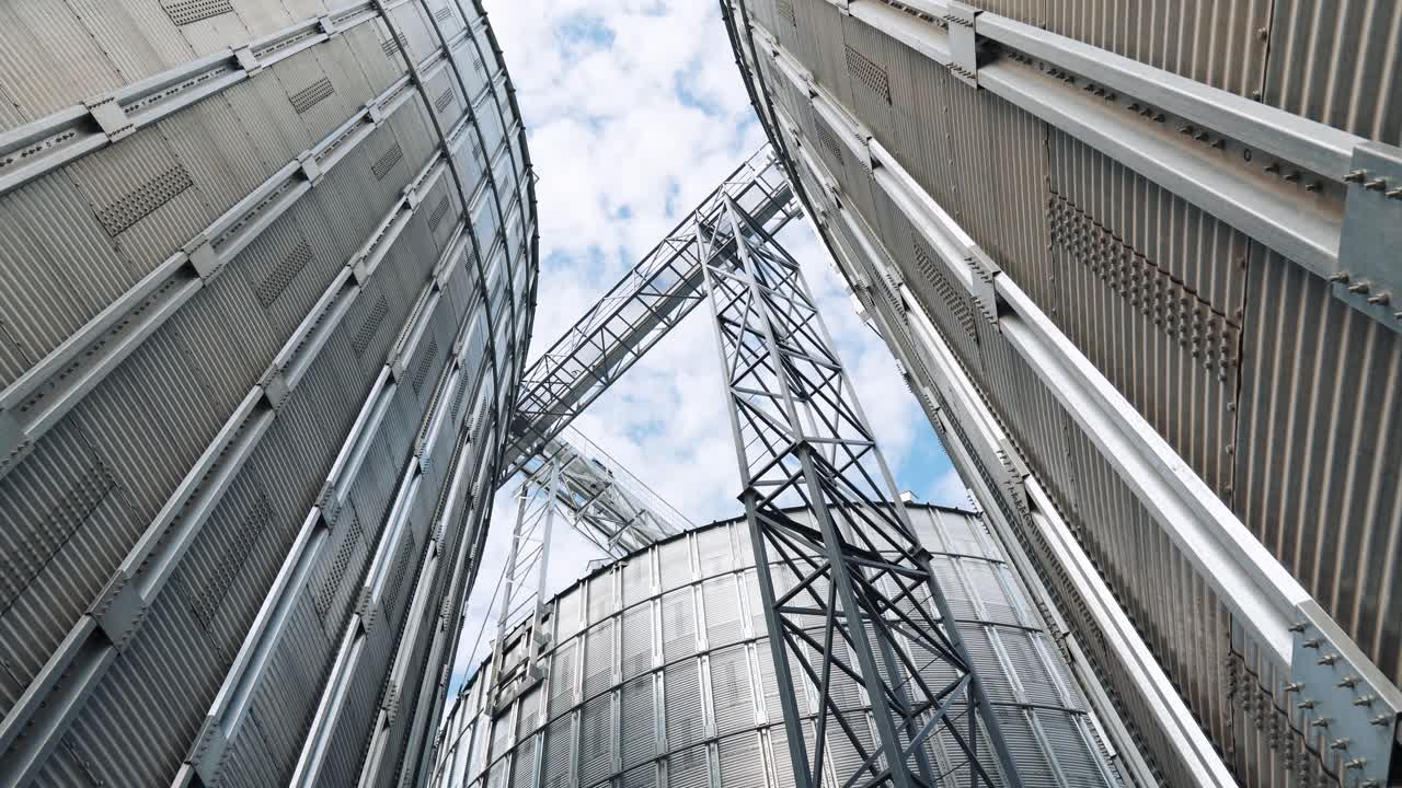 Exterior of a modern agricultural factory. Silver grain elevators. Large metal silos for grain processing. Close-up