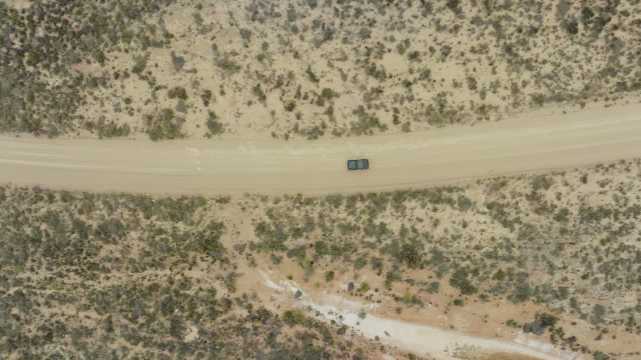 드론은 남아프리카 공화국의 세더버그 야생 지역에서 검은색 오프로드 차량이 운전하는 도로 위에서 새의 눈으로 날아갑니다.