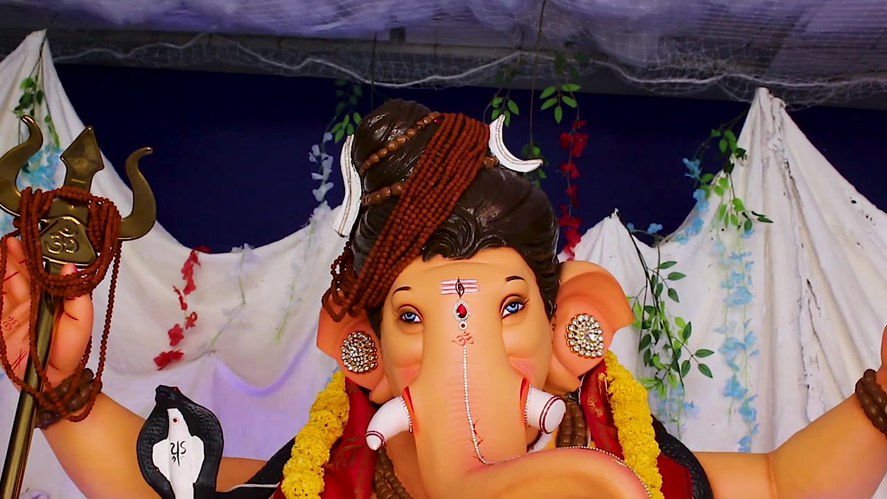 Primo piano del volto di un idolo di Ganesh vestito come Lord Shiva con i segni del tripundra sulla fronte e la luna crescente, ripresa dal basso che rivela un'espressione divina durante il Ganesh Chaturthi in India