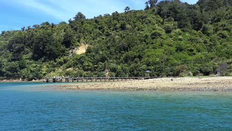 beautiful deep blue sea changing to turquoise with lush green vegetation and jetty at ship cove