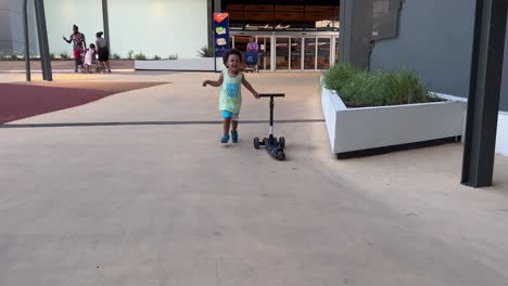 Two-year-old-exotic-and-cute-african-europoean-child-playing-happy-with-his-first-skateboard-in-a-hot-summer-day,-outdoor