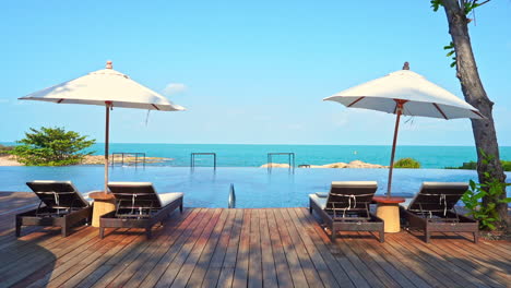 Tumbonas-Y-Sombrillas-Junto-A-La-Piscina-Con-Hermosas-Vistas-Al-Mar-Azul