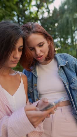 two young women looking at a phone outdoors